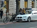 Kép a BMW motorháztetején ülő kerékpáros lányról
